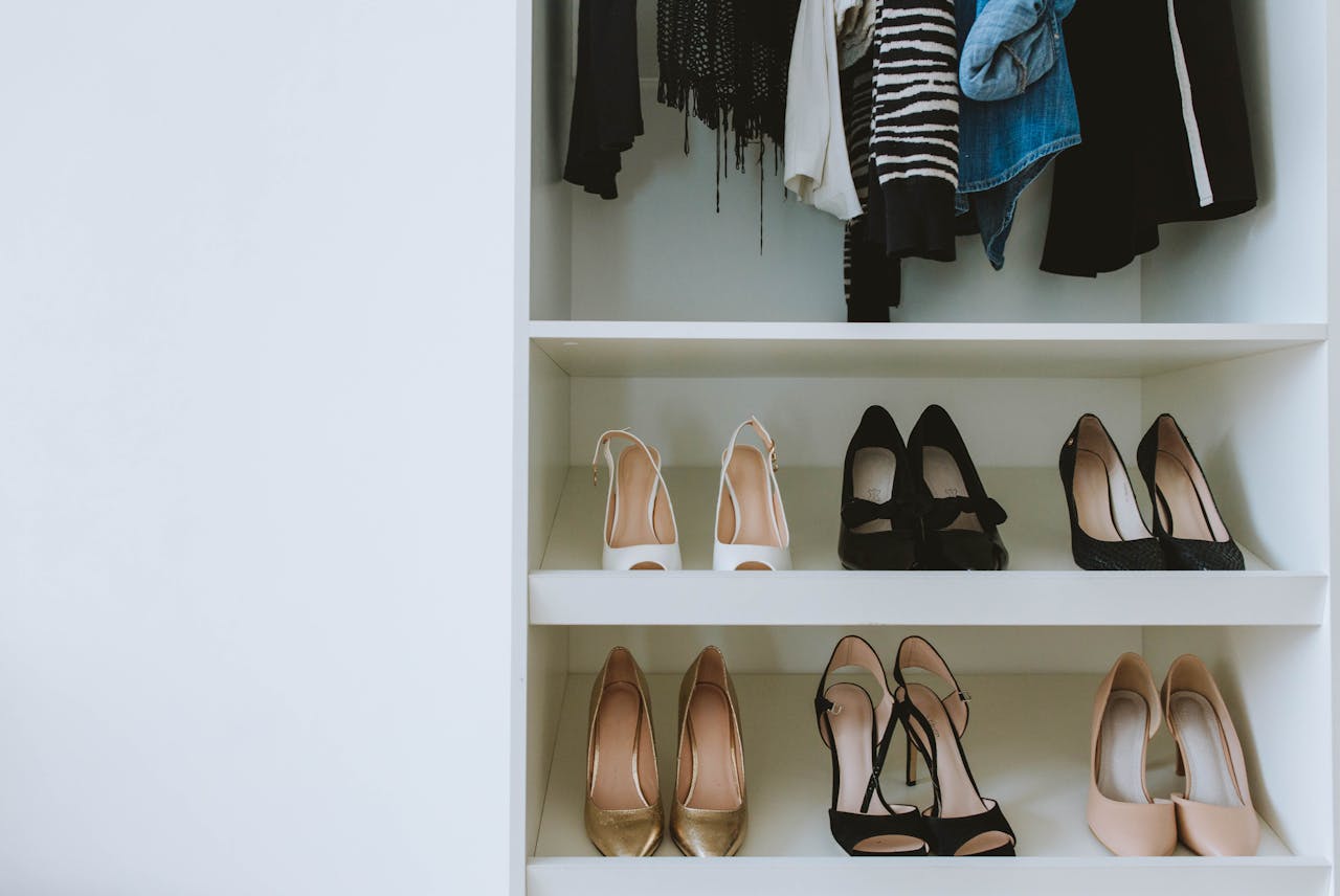 services-03 A neatly organized closet with high heels and assorted clothes on shelves.